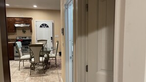A kitchen with wooden cabinets, a stove, and a dining area with a table and chairs. - Affordable guest house  (Perris)