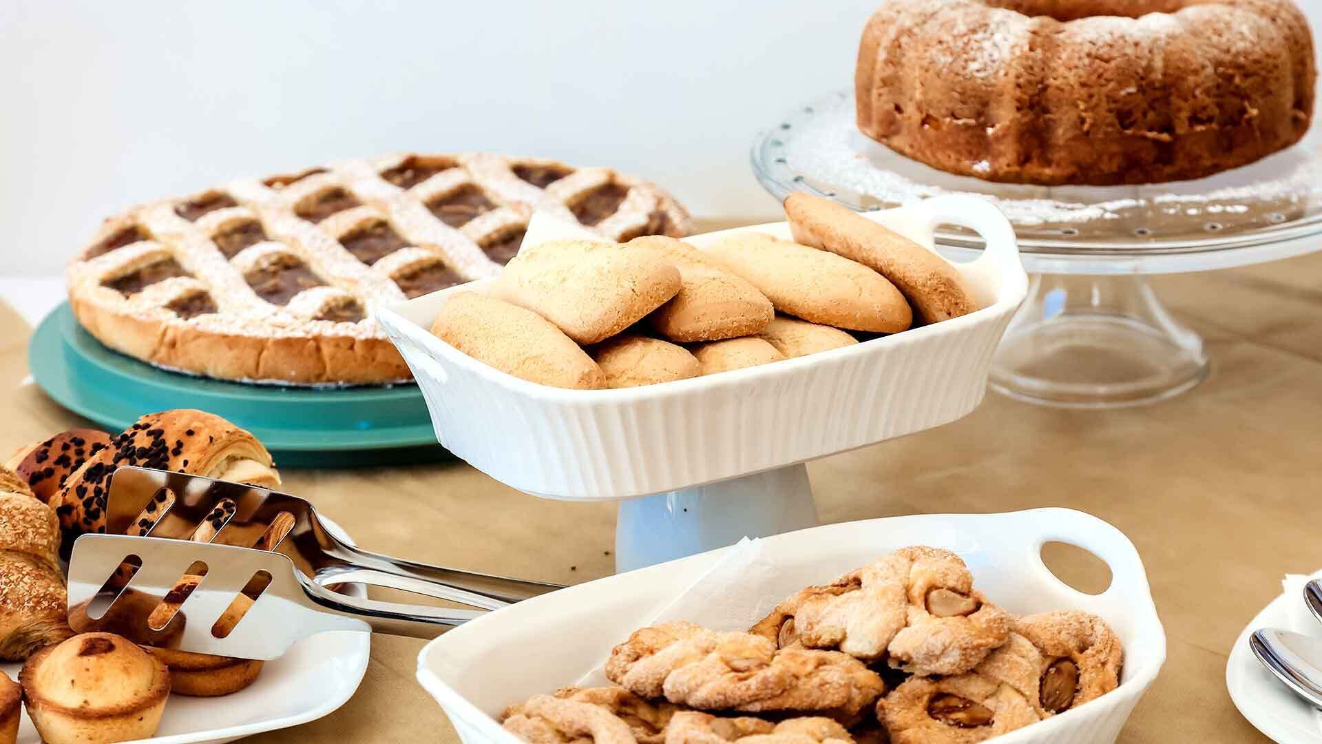 A variety of baked goods including a lattice-topped pie, a bundt cake, and several types of cookies and pastries.