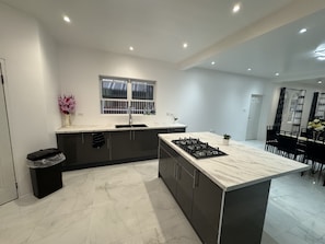 A modern kitchen with a central island, dark cabinets, and a window above the sink.