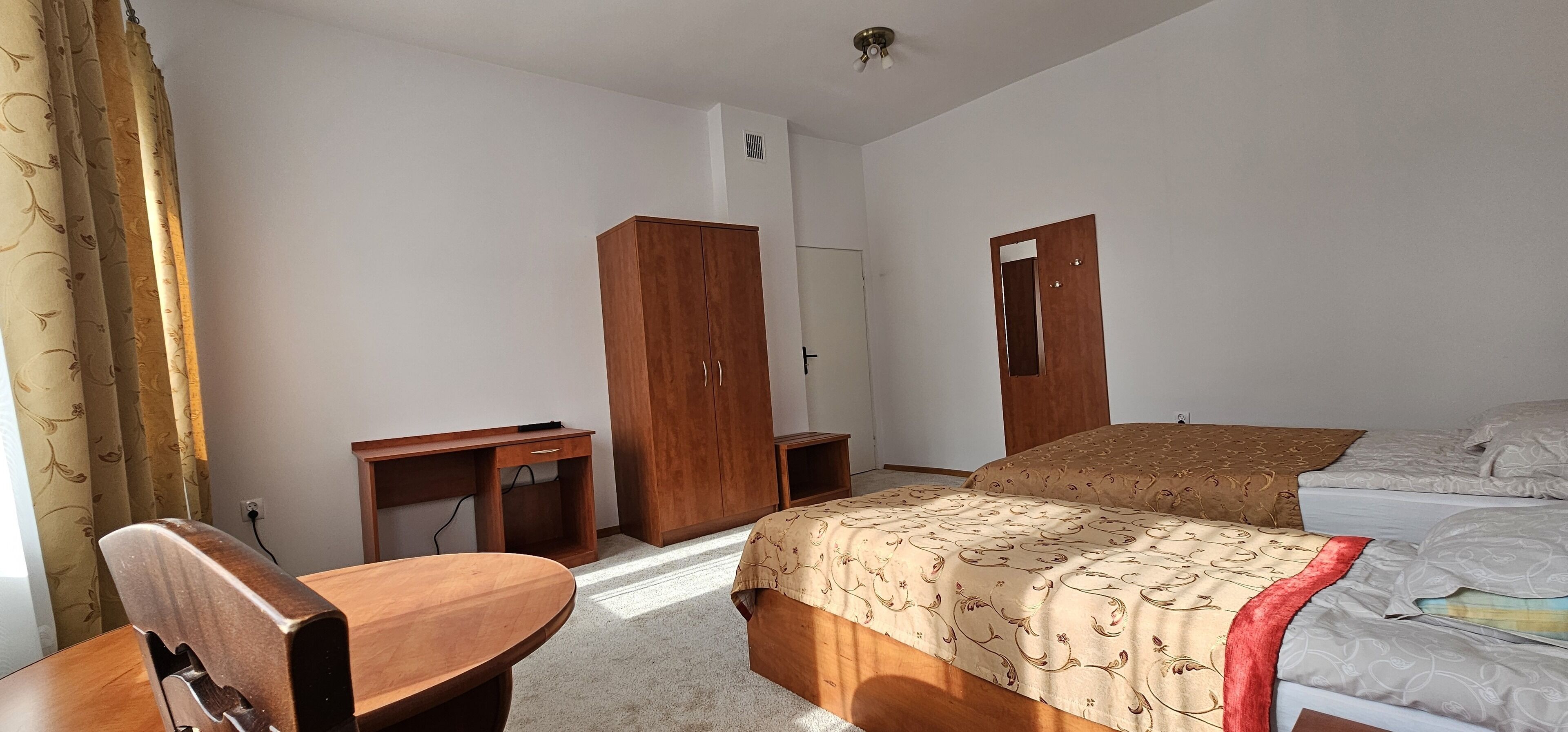 A hotel room with a bed, a desk, a wardrobe, and a chair.