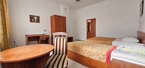 Una habitación de hotel con cama, escritorio, silla y una mesita.
