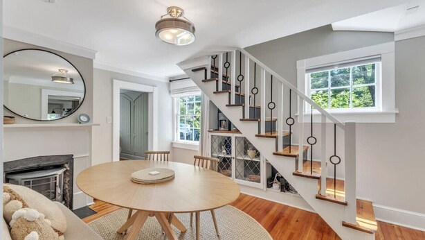 Un salon moderne avec une table ronde en bois, une cheminée et un escalier au design original.