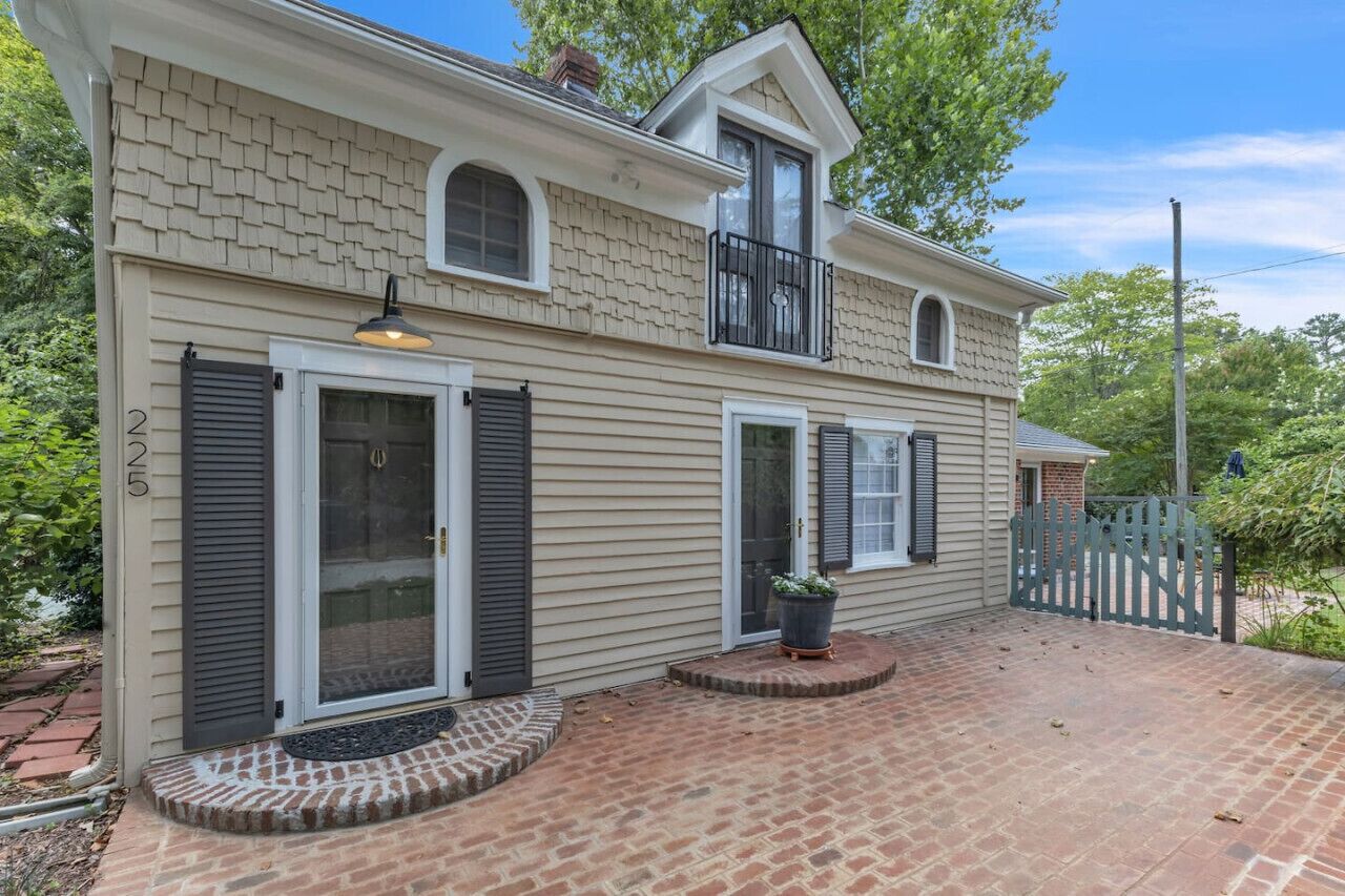 Une maison à deux étages avec une terrasse en briques, une porte d’entrée dotée d’une vitre et un petit balcon.