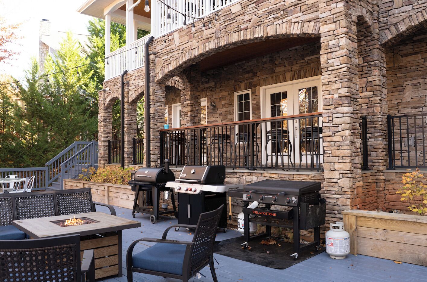 An outdoor patio with stone walls, a grill, and a fire pit.