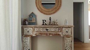 Una consola de madera rústica blanca con detalles decorativos y un espejo redondo encima.