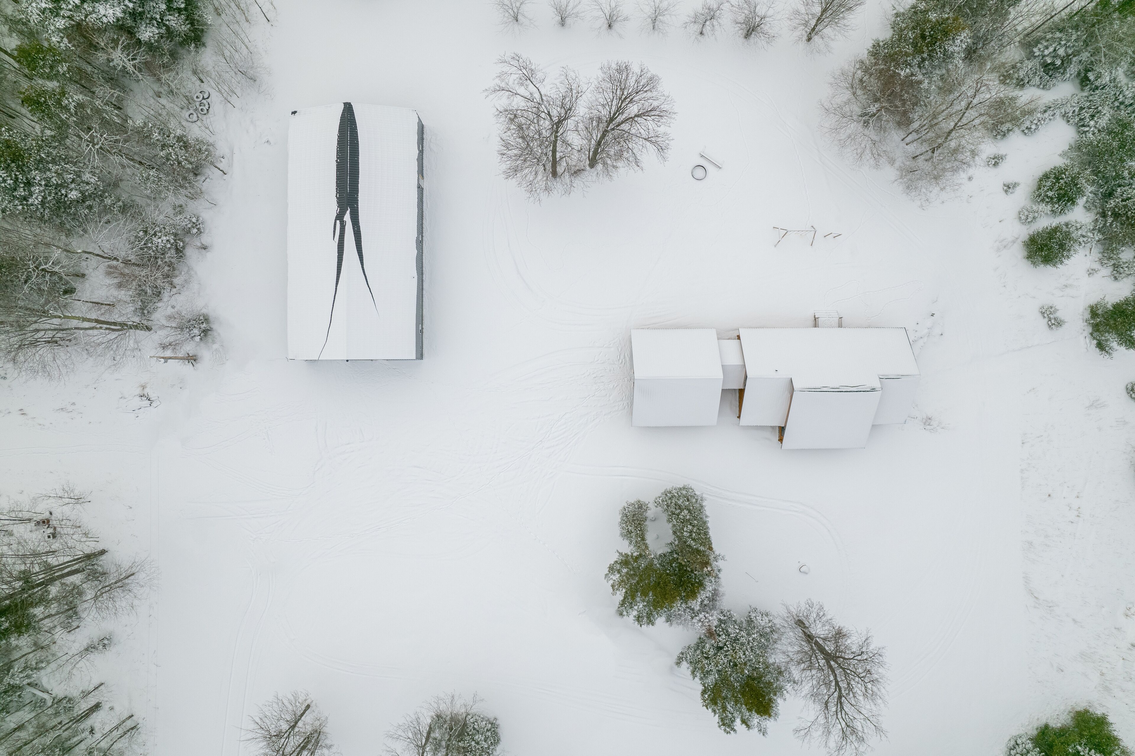 An aerial view of a snow-covered property with a large white structure and a smaller building.