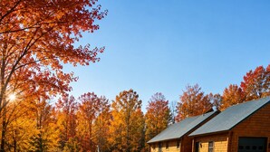 A rustic cabin with a stone foundation, a metal roof, and a front porch.