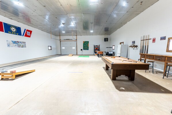 A spacious indoor area with a pool table, a billiards rack, and a dartboard.