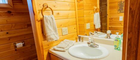 Bagno di una cabina in legno con lavandino, specchio e lampade a sospensione.
