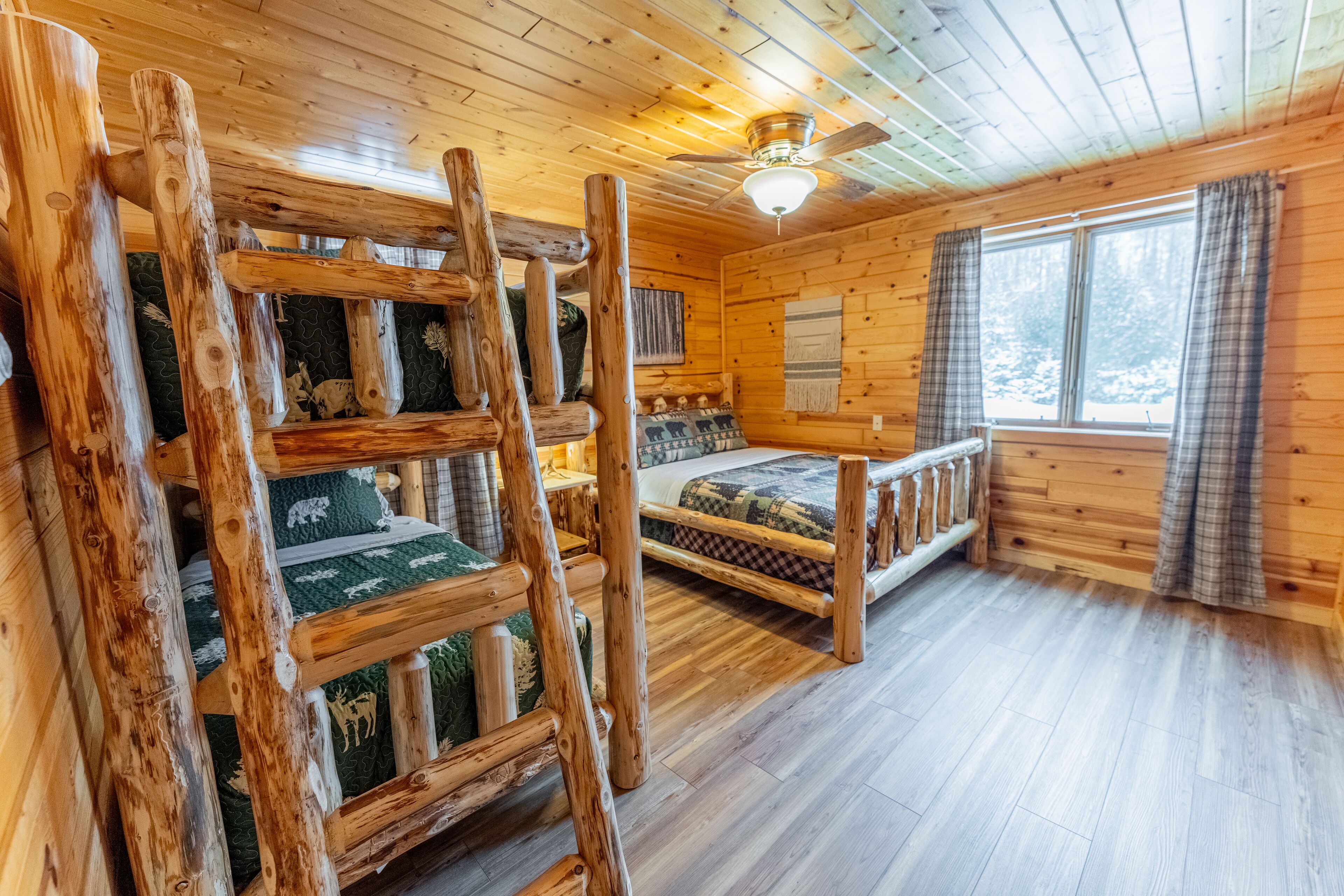 Een chalet met een vide, een ladder, een plafondventilator en een raam met gordijnen.