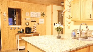 Una cocina con armarios de madera, encimera de granito, cafetera y varios letreros de cocina.