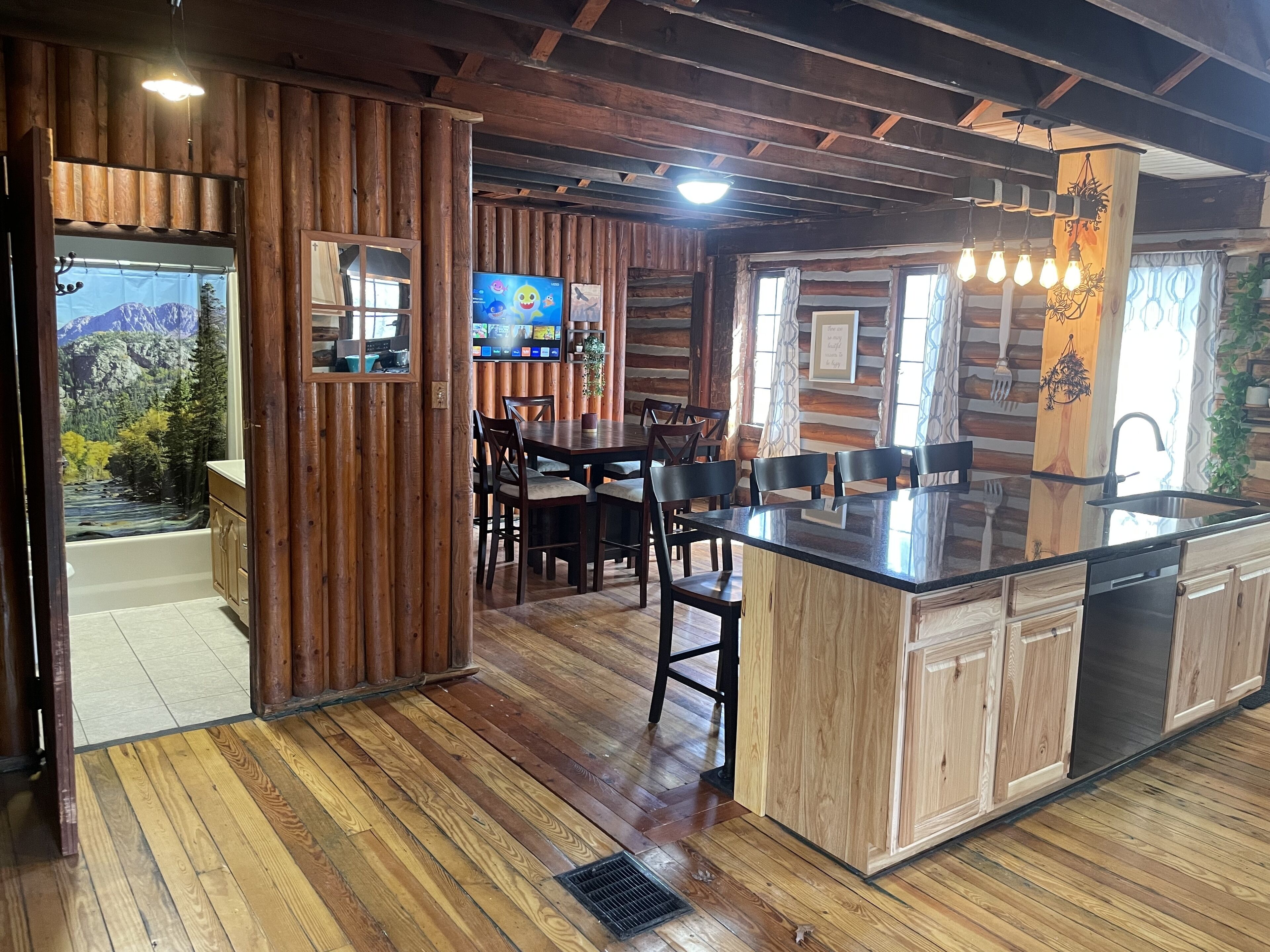 Un interno rustico con zona pranzo in legno, cucina con isola centrale ampia e bagno con vista sulle montagne.