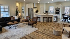 A modern kitchen with a central island, built-in appliances, and a dining area with bar stools. - Silver Lake & Dunes Dream House (Mears)