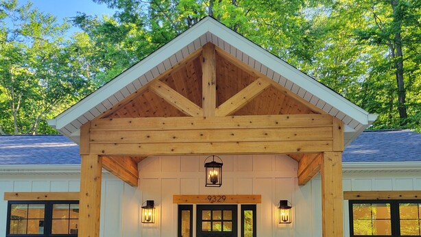 A wooden house with a covered porch, a black front door, and two potted plants. - Silver Lake & Dunes Dream House (Mears)
