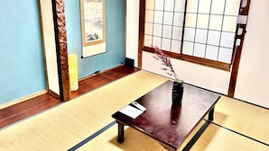 Een traditionele Japanse kamer met tatami vloerbedekking, een shoji-scherm, een schuifdeur en een kleine tafel met een vaas.