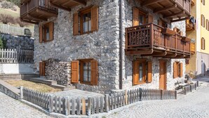 A stone building with wooden balconies and a cobblestone street. - Casa Roberto (Moena)