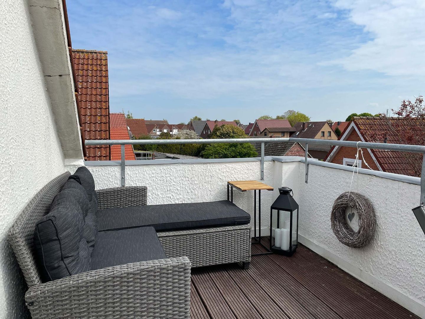 Un balcon avec un canapé en osier, une petite table et une lanterne.