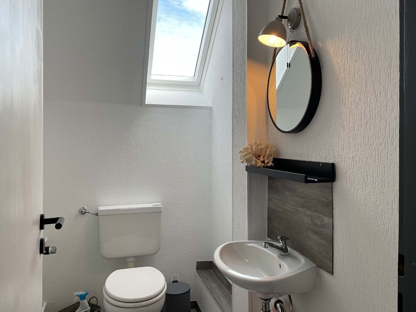 A modern bathroom with a toilet, sink, and a mirror.