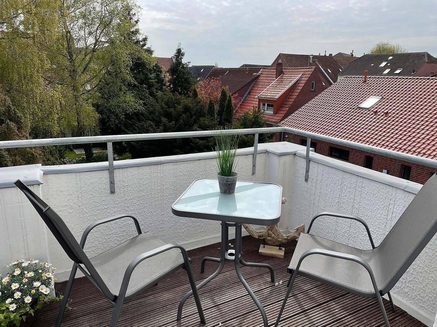 Ein Balkon mit zwei Stühlen, einem kleinen Tisch und einem Blumentopf.