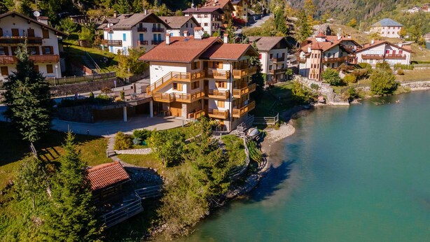 Un pueblo en una ladera con edificios de estilo chalé tradicional, un río y montañas al fondo.