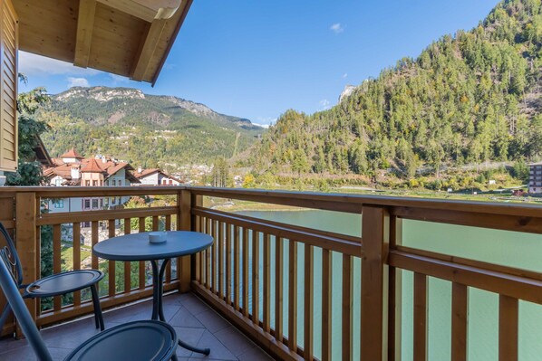 Een balkon met uitzicht op een rivier en bergen.