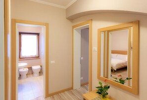 A hotel room with a bathroom, a bed, and a mirror. - Regina 4 (Alleghe)