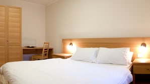 A bedroom with a bed, two bedside tables, a wooden nightstand, a wooden chair, and a wooden wardrobe. - Regina 4 (Alleghe)