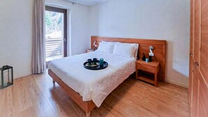 A bedroom with a wooden bed, a nightstand, a bedside table, a window with curtains, and a tray with cups and a teapot on the bed. - Regina 13 (Alleghe)
