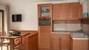 A compact kitchen with wooden cabinets, a built-in oven, a microwave, and a sink.