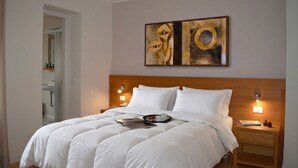 A neatly made bed with white linens, a wooden headboard, and two bedside lamps. - Regina 10 (Alleghe)