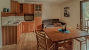 Eine kleine Küche mit Holzausbau, einem eingebauten Backofen und einem Essbereich mit Holztisch und Stühlen.