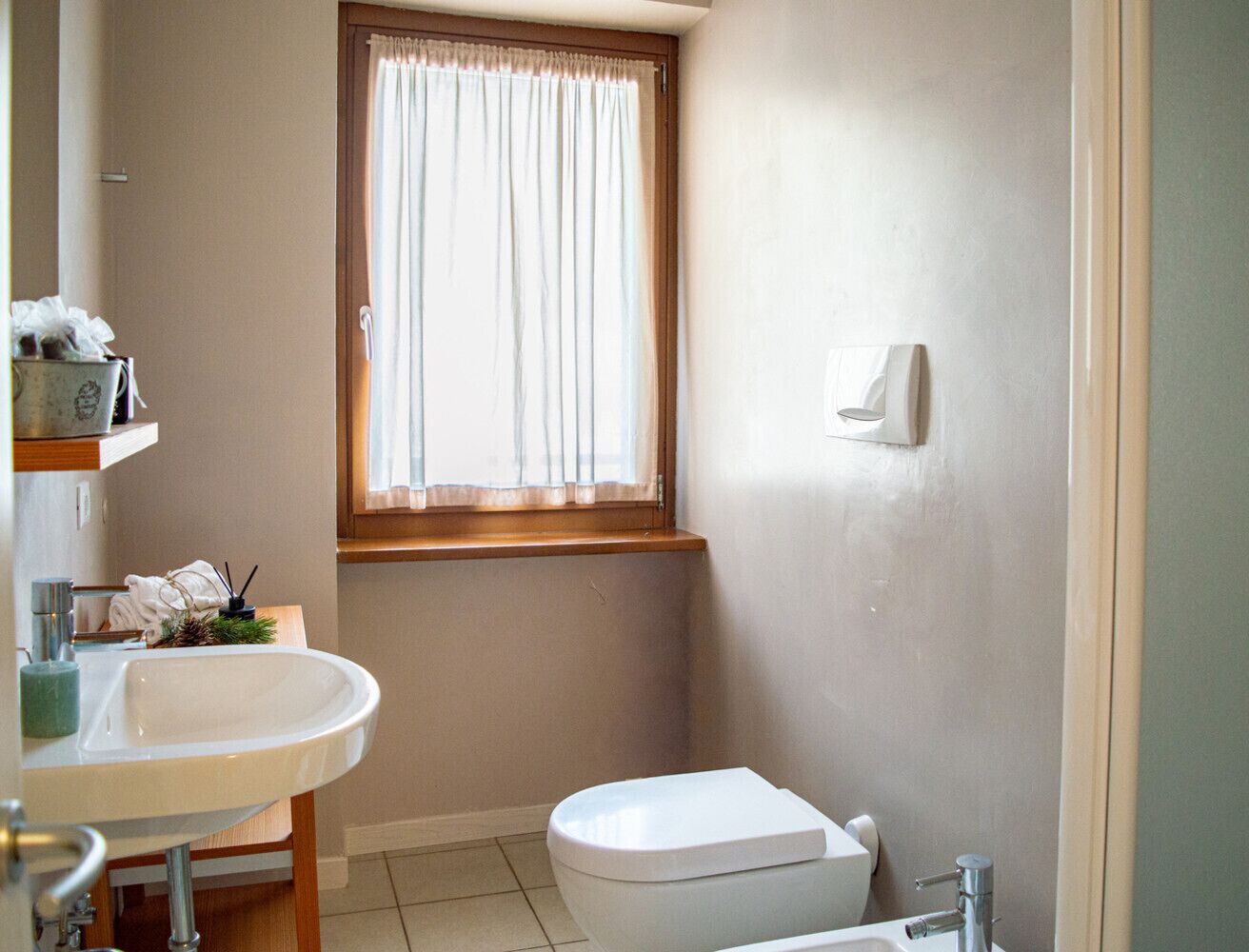 A bathroom with a toilet, sink, and window.