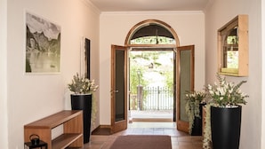 A hallway with a bench, potted plants, a rug, and a view of the outside. - Regina 20 (Alleghe)