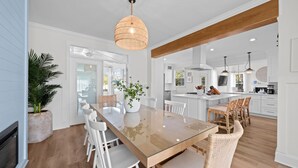 Een moderne keuken met witte kasten, een houten kookeiland en hanglampen.