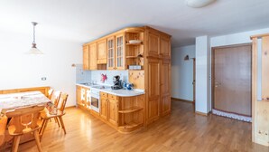Eine kompakte Küche mit Holzschränken, einer weißen Arbeitsplatte und einem Essbereich mit Holzkufen.