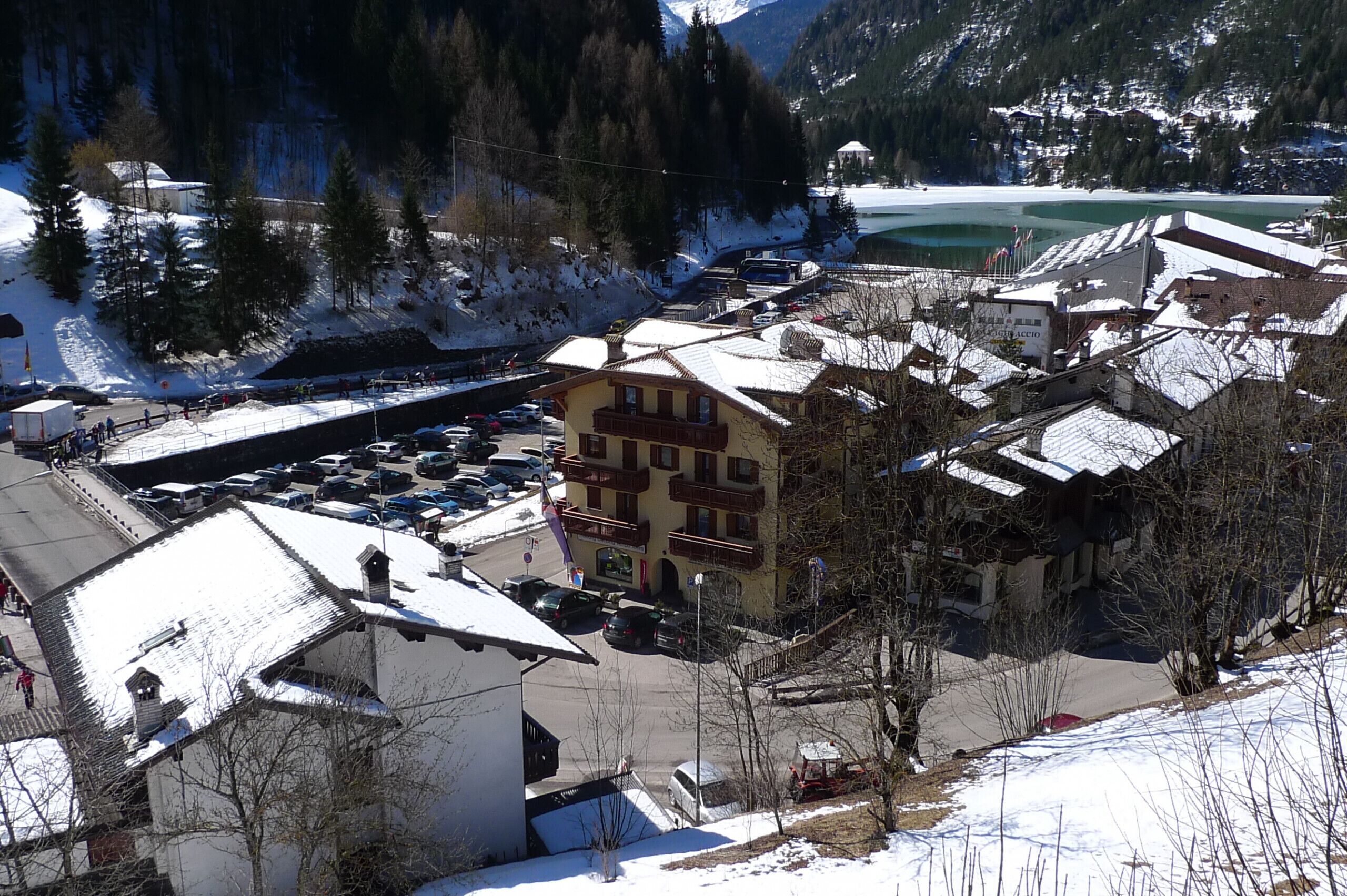 Un pueblo cubierto de nieve con un edificio destacado que tiene varios balcones y un estacionamiento.