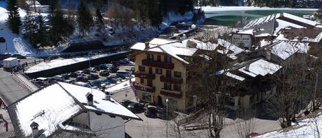 Un pueblo cubierto de nieve con un edificio destacado que tiene varios balcones y un estacionamiento.