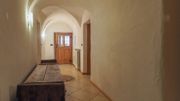 A hallway with a wooden bench, a door with glass panels, and a radiator on the wall. - Casa Cristina (Campitello di Fassa)