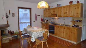 Eine gemütliche Küche mit Holzausbau, einem Esstisch mit Stühlen, einer Hängeleuchte und einem Fenster mit Blick.