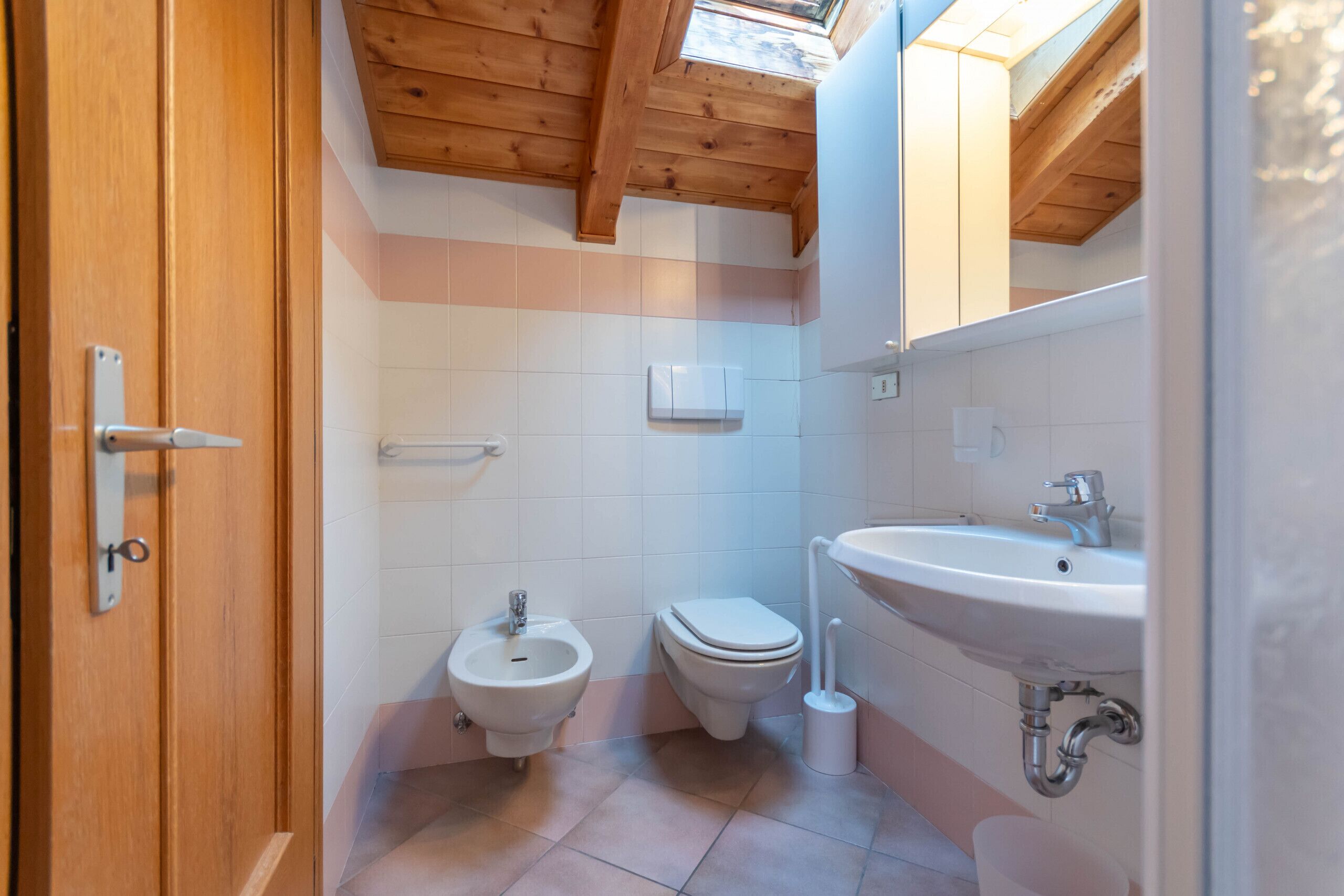 Ein Badezimmer mit Holzboden, einem Bidet, einer Toilette und einem Waschbecken.