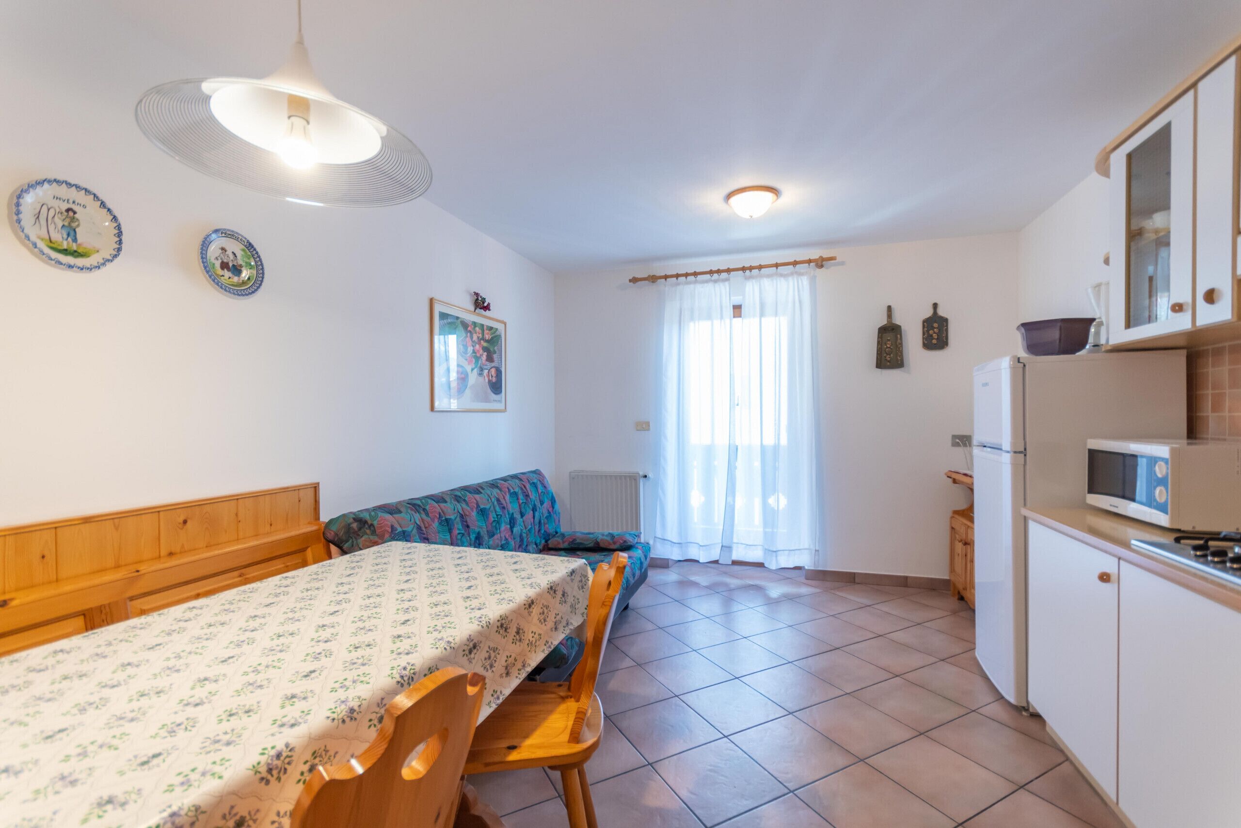 Cocina compacta con comedor, que incluye una mesa con sillas, un sofá y un refrigerador.
