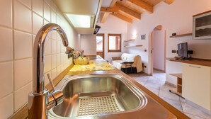 Una cocina moderna con un lavamanos de acero inoxidable, vigas de techo de madera y vista al área de estar.