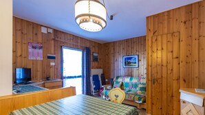 A wooden-paneled room with a bed, a desk, a chair, and a television.