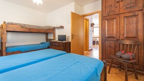 A bedroom with two bunk beds, a wooden wardrobe, and a chair with bags. - Dimora al Villaggio (Mazzin)