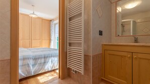 Une chambre à coucher avec un lit, une armoire en bois et une salle de bain équipée d’un lavabo et d’un miroir.