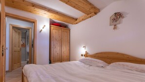 Een slaapkamer met een houten bed, een kledingkast en een douche die door een open deur zichtbaar is.