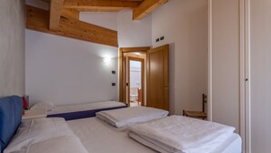 Ein Zimmer mit zwei Betten, Holzbalken an der Decke, einer Tür und einem kleinen Tisch.