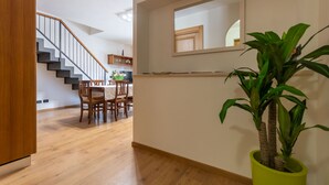 Ein modernes Interieur mit einer Treppe, einem Holzespeisetisch, Stühlen und einem Blumentopf.
