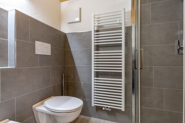 Een moderne badkamer met toilet, handdoekhouder en douche.