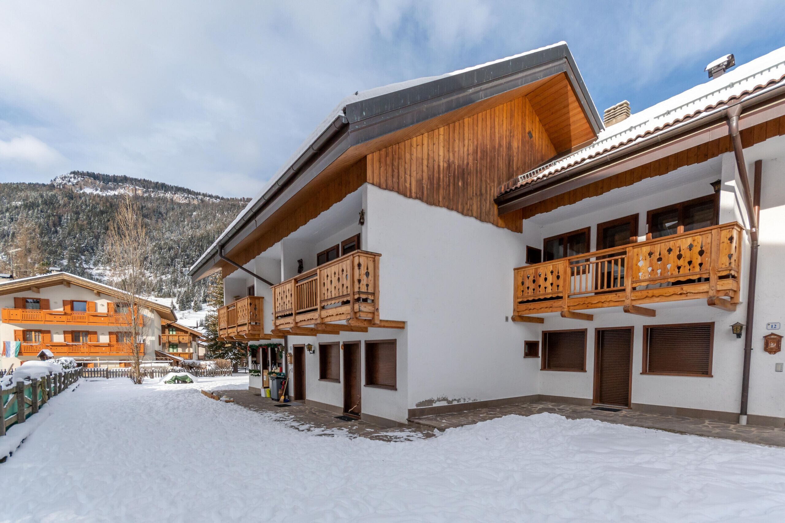 A snow-covered courtyard with wooden balconies and a mountain backdrop.